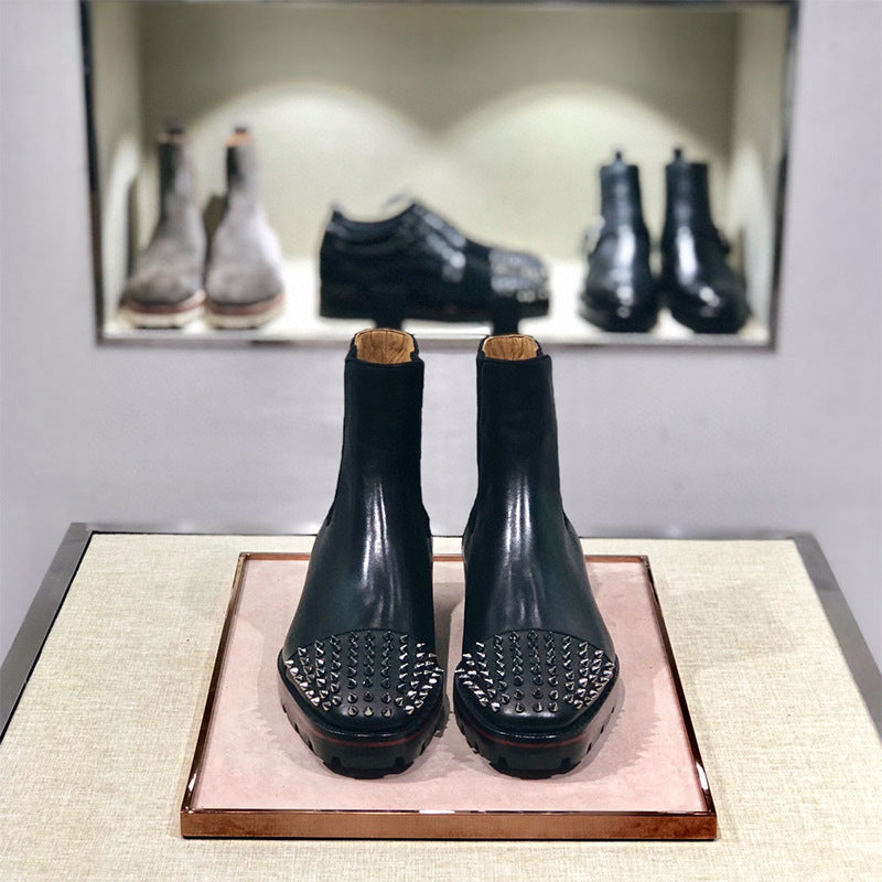 Pair of black leather boots with cork soles on a display stand, with a mirror reflecting more shoes in the background.