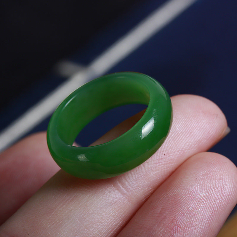 Green ring held between fingers against a dark background