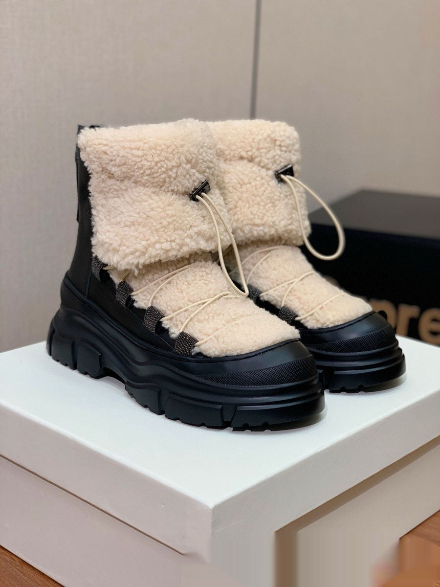 Black and beige winter boots on a white platform with a neutral background