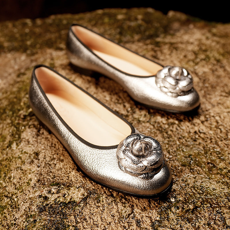 Silver shoes with floral embellishments on a textured surface