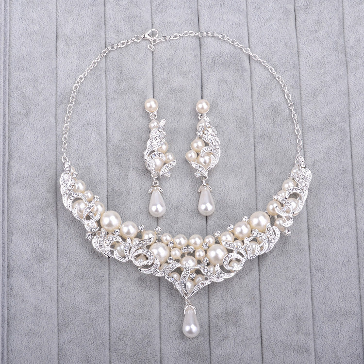 Pearl and crystal necklace and earrings set on a gray background