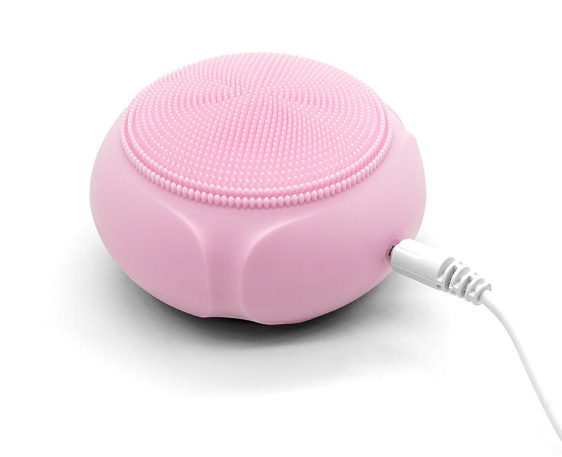 Pink silicone cleaning pad with charging cable on a white background