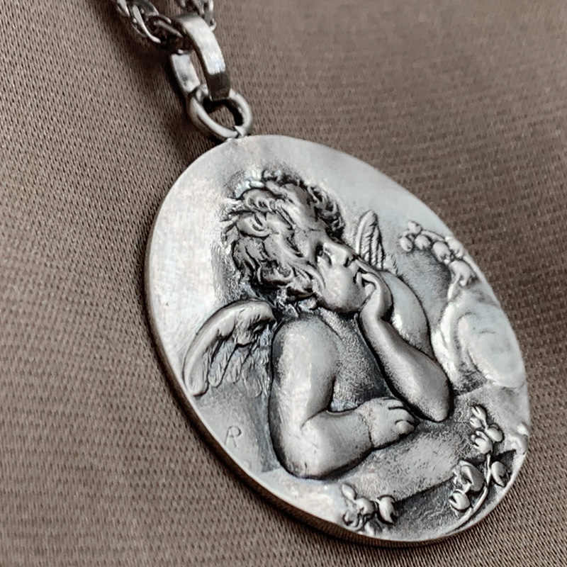 Silver pendant with an angelic design on a brown background