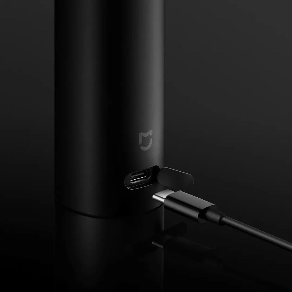 Black cylindrical device with USB-C cable on a dark background