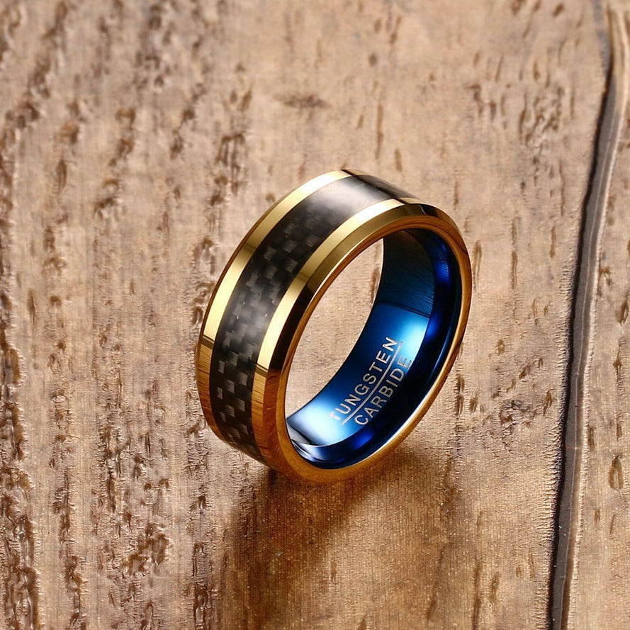 Gold and blue ring with carbon fiber inlay on a wooden surface