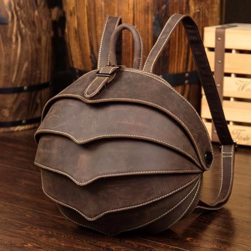 Brown leather backpack on a wooden surface with wooden barrels in the background