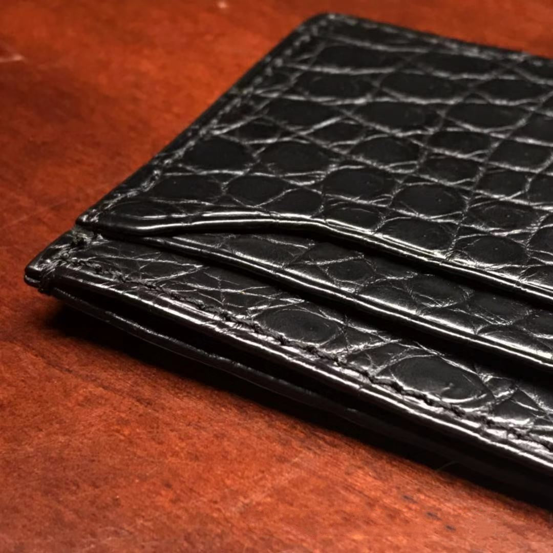 Black crocodile skin wallet on a wooden surface