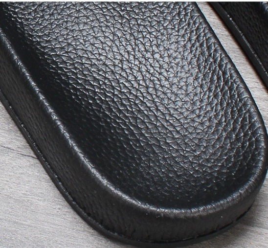 Close-up of a black leather sandal sole on a light wooden surface
