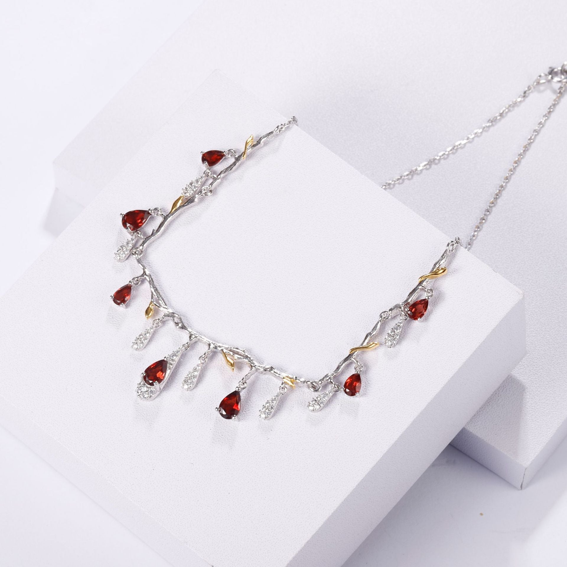 Necklace with red and clear stones on a white surface