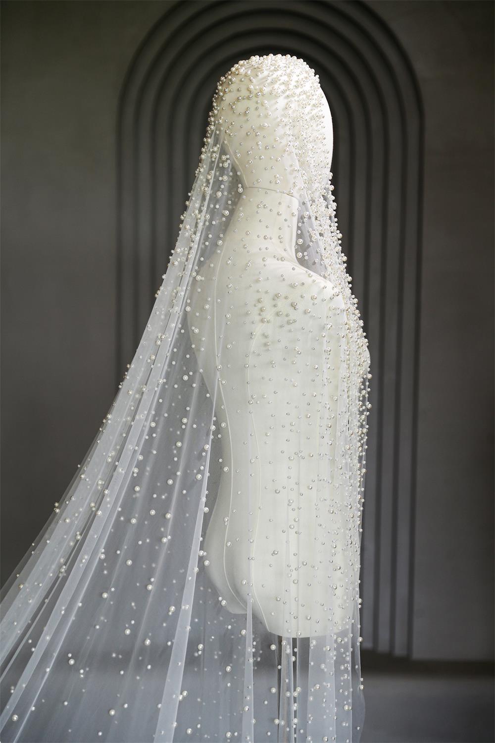 White wedding dress with a long veil on a mannequin against a dark background