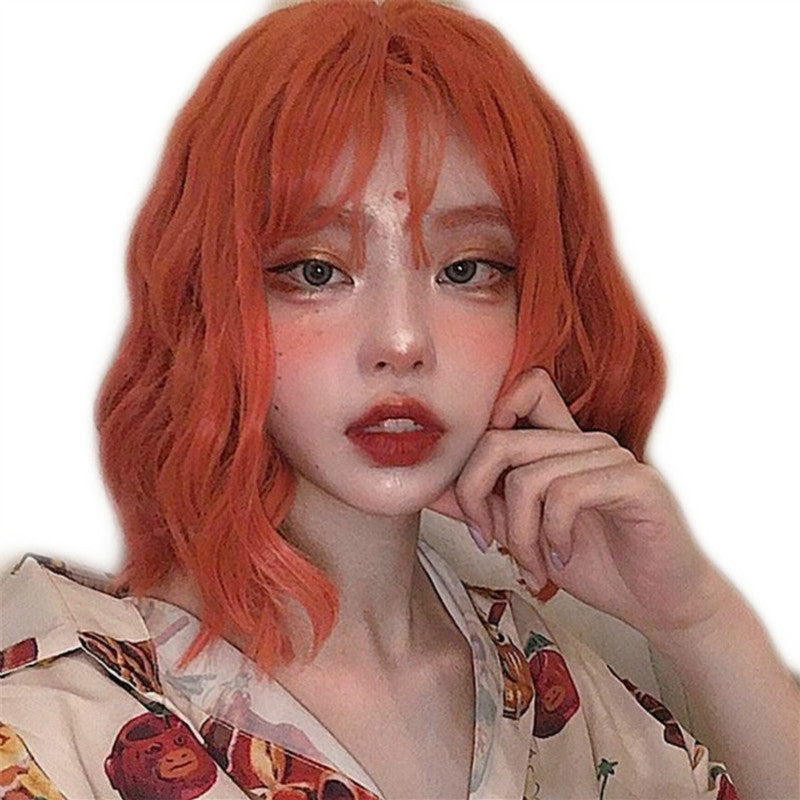 Person with orange hair wearing a patterned shirt on a white background