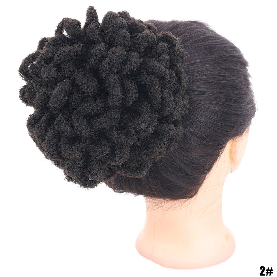 Black textured hairpiece on a mannequin head against a white background