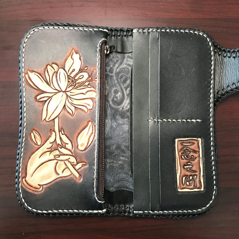 Black leather wallet with floral design and gold accents on a wooden surface