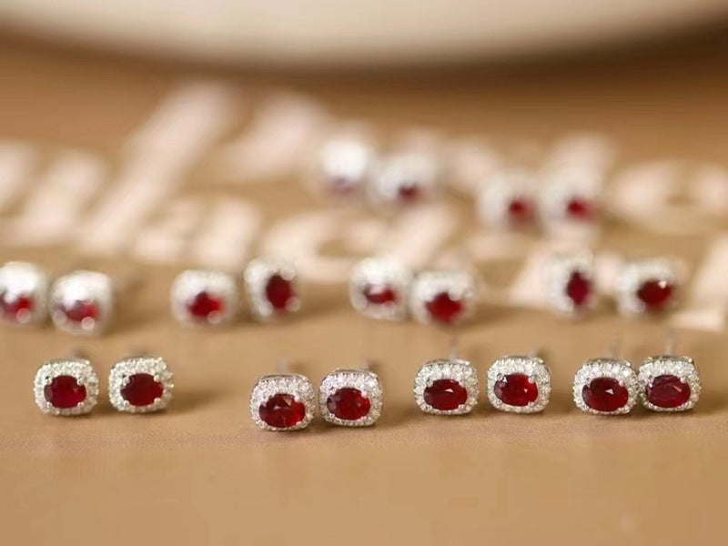 Red gemstone earrings with silver settings on a beige background