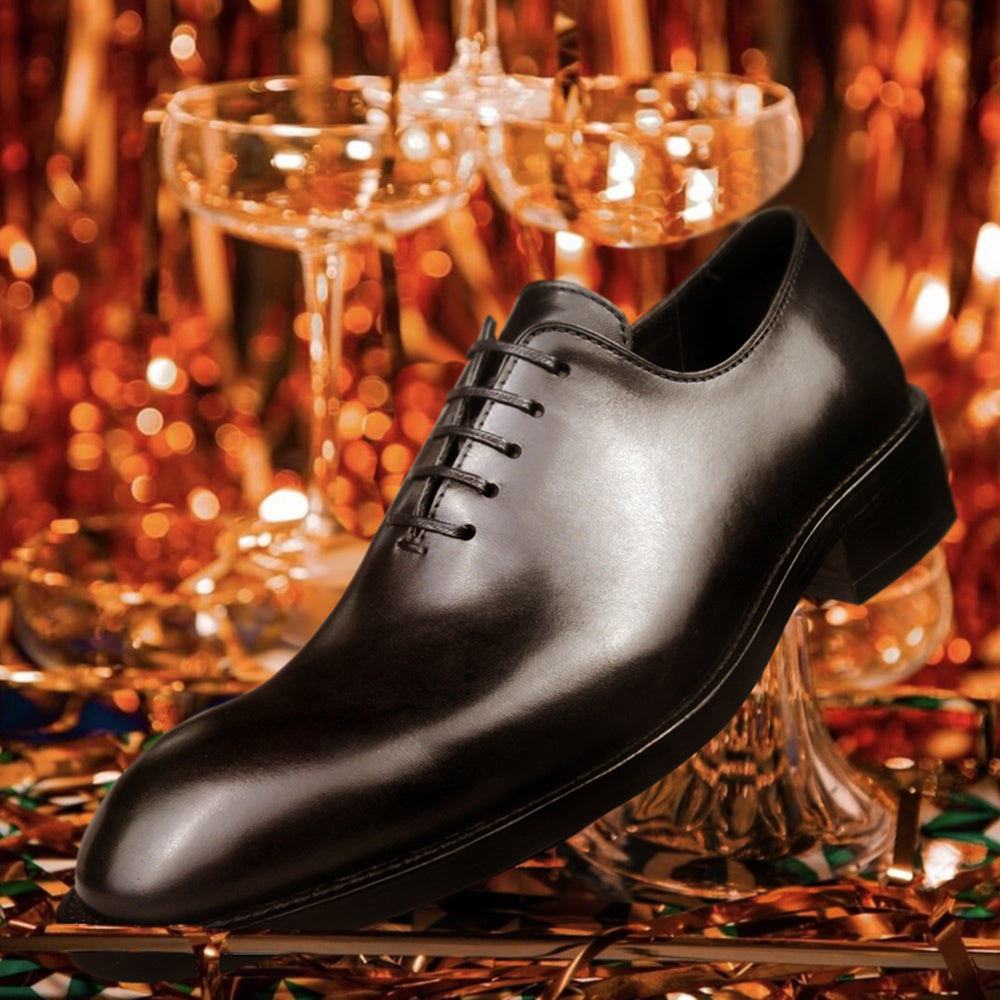 Black dress shoe on a decorative background with glasses and lights