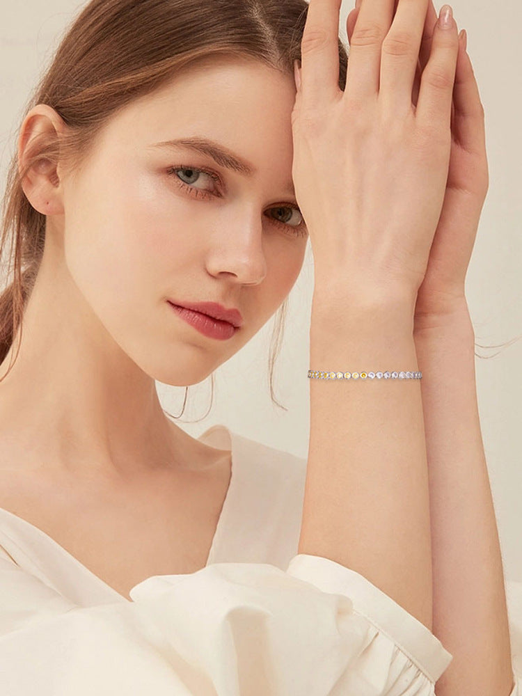 Woman wearing a delicate bracelet on a plain background