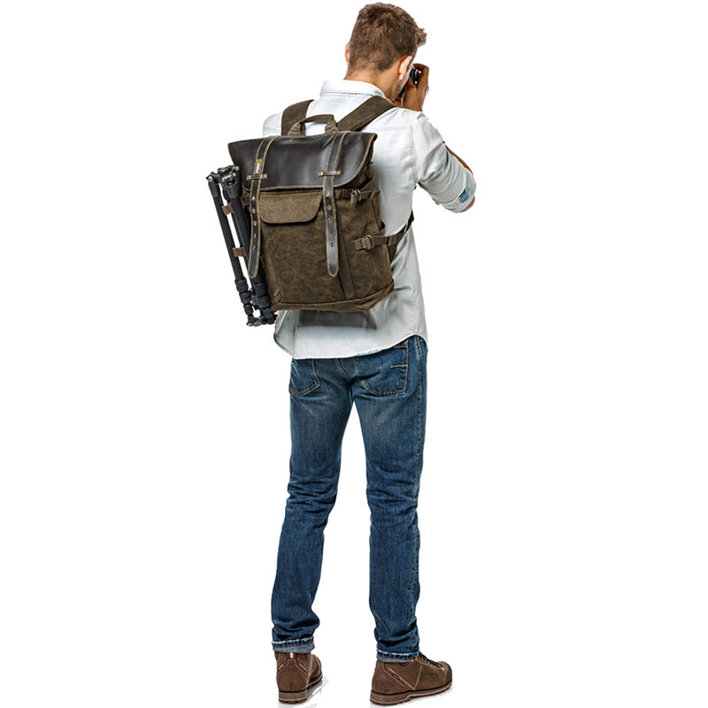 Man with a large brown backpack holding a camera on a white background