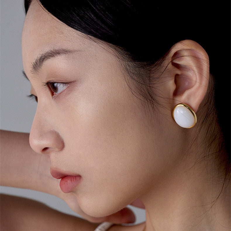 Close-up of a woman wearing a gold earring with a white stone.