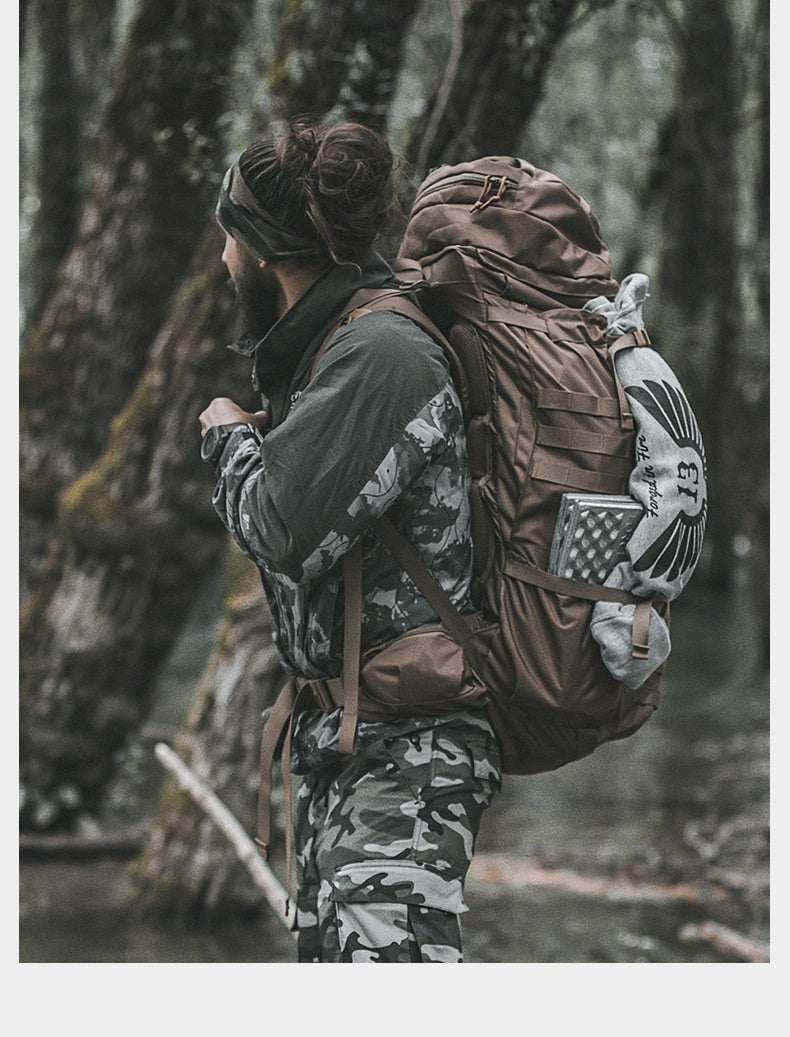 Person in camouflage clothing and carrying a large backpack in a forest setting