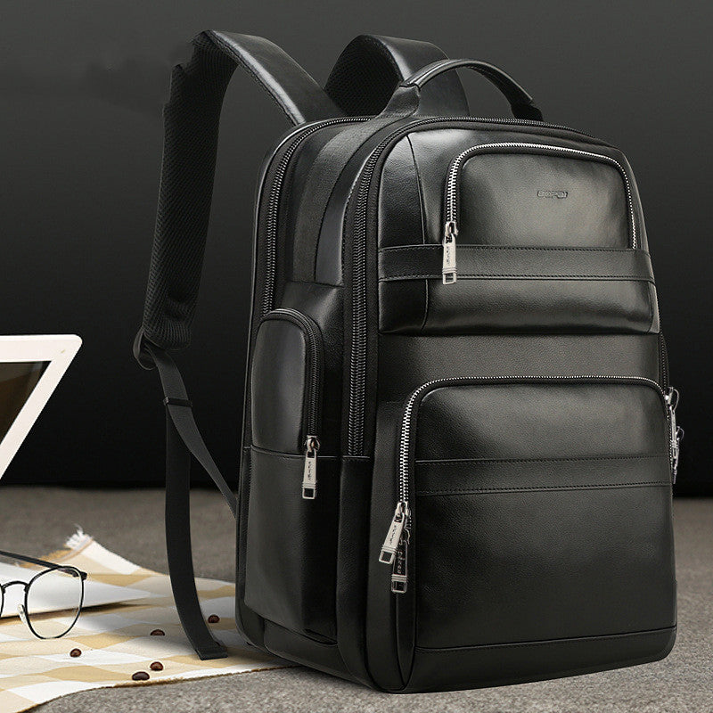 Black leather backpack on a dark background with a laptop and glasses.
