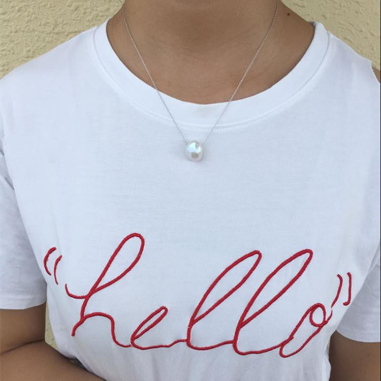 White t-shirt with red 'hello' text worn by a person, against a neutral background