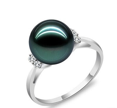 Silver ring with a large green pearl and smaller diamonds on a white background
