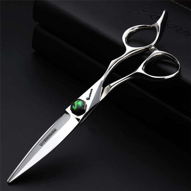 Silver scissors with a green gemstone on a black background