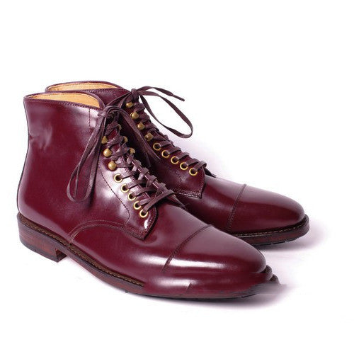 Pair of maroon leather boots with laces on a white background