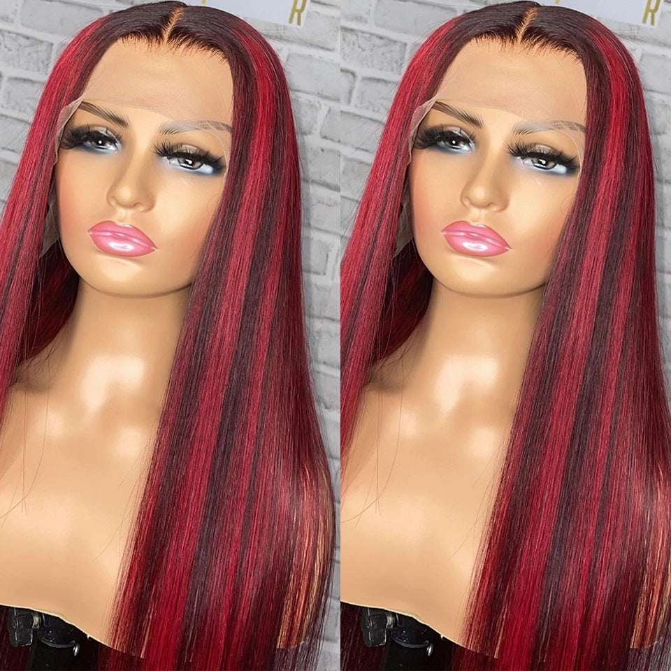 Two mannequin heads with red and black wigs against a gray brick wall.