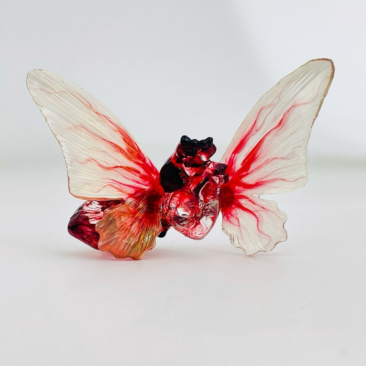 Glass butterfly figurine with red and clear wings on a white background