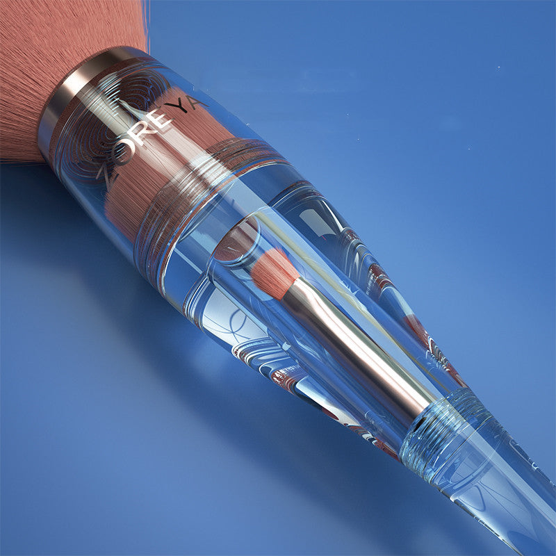 Makeup brush with clear handle and wooden bristles on a blue background