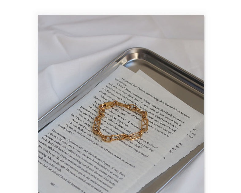 Gold chain bracelet on a book with a white background