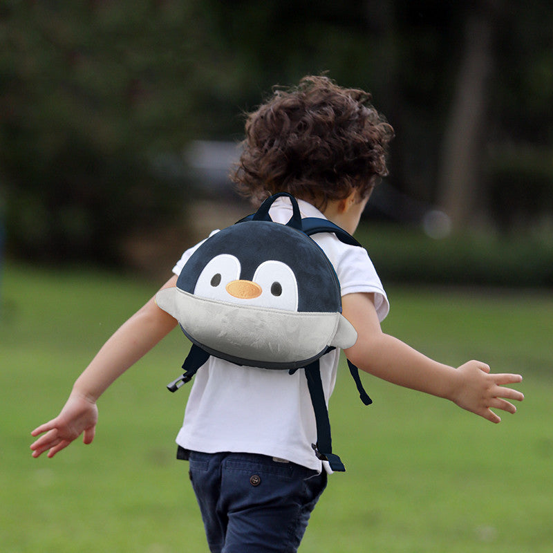 Child running outdoors with a penguin backpack