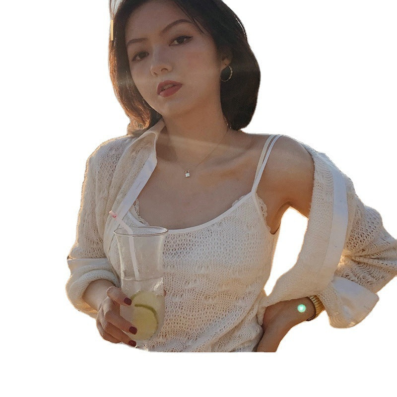 Woman in a white lace top holding a drink against a plain background