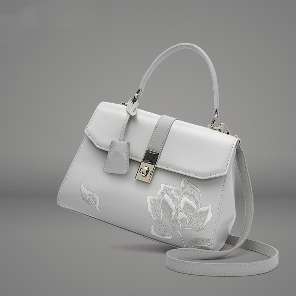 White handbag with floral embroidery on a gray background