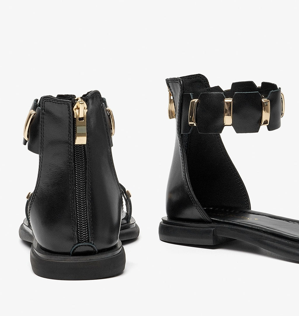 Black ankle boots with gold accents on a white background