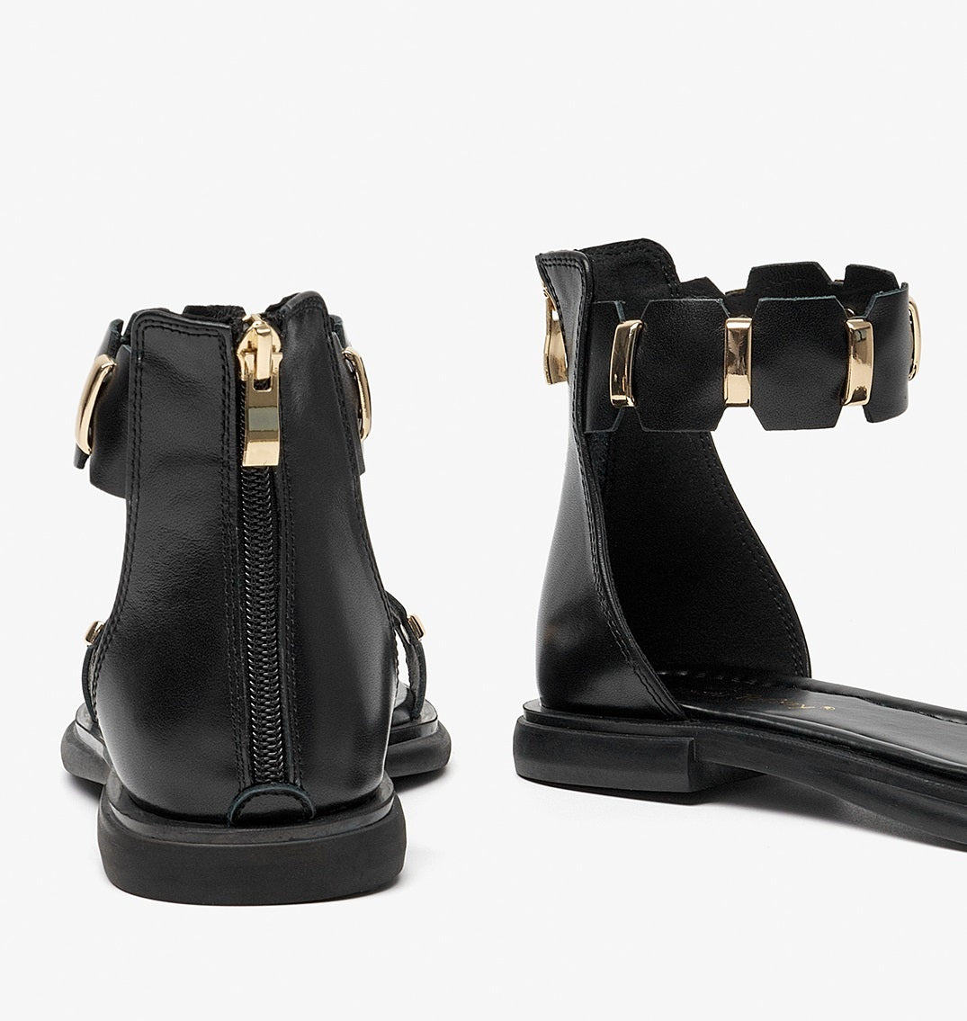 Black ankle boots with gold accents on a white background