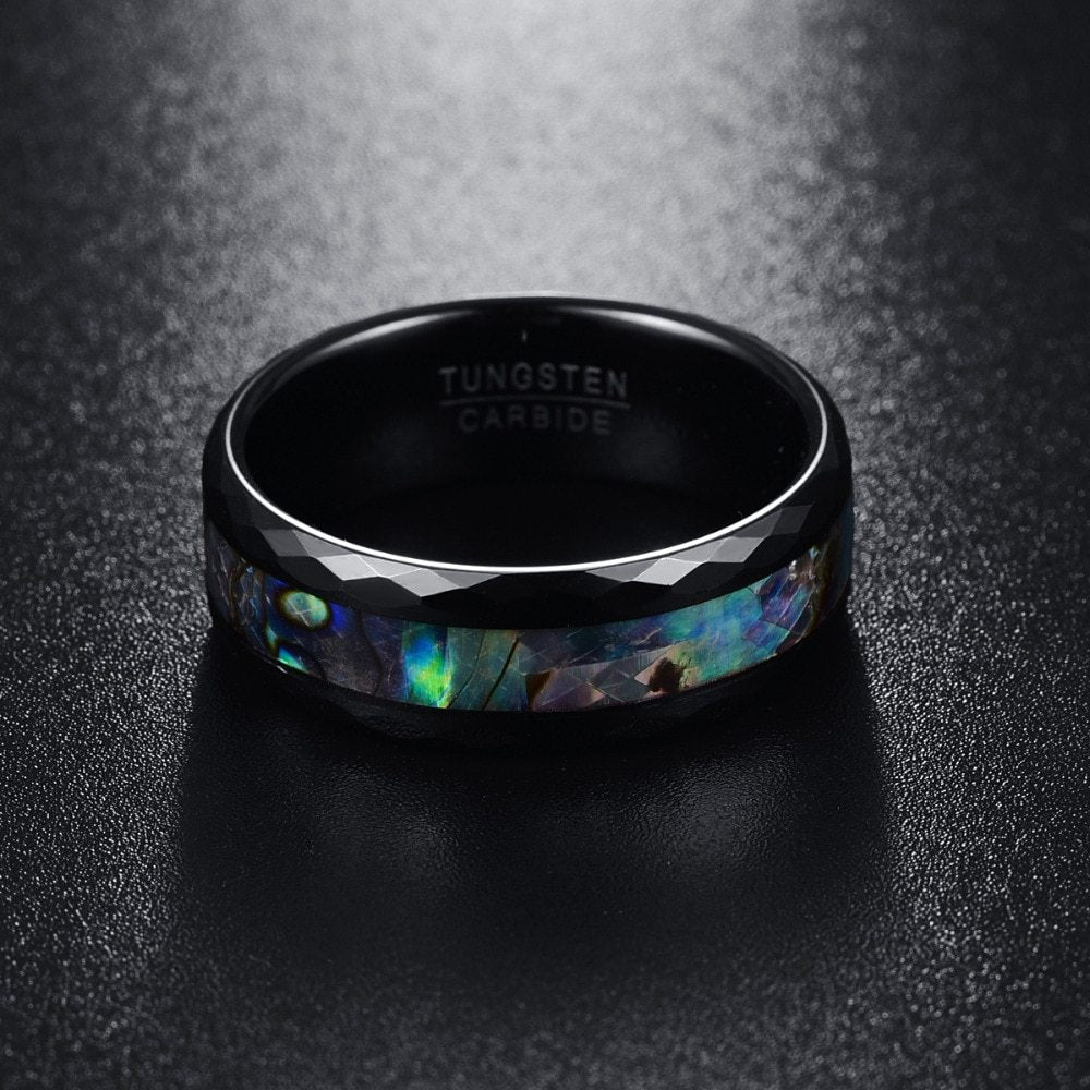 Black tungsten carbide ring with opal inlay on a dark textured background