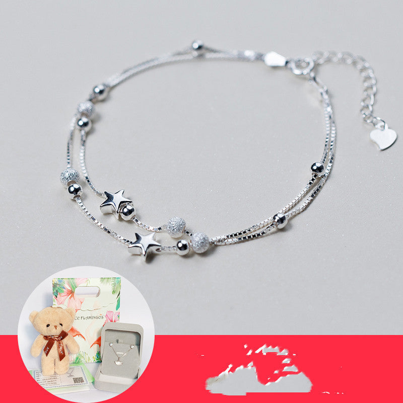 Silver bracelet with star and heart charms on a gray background
