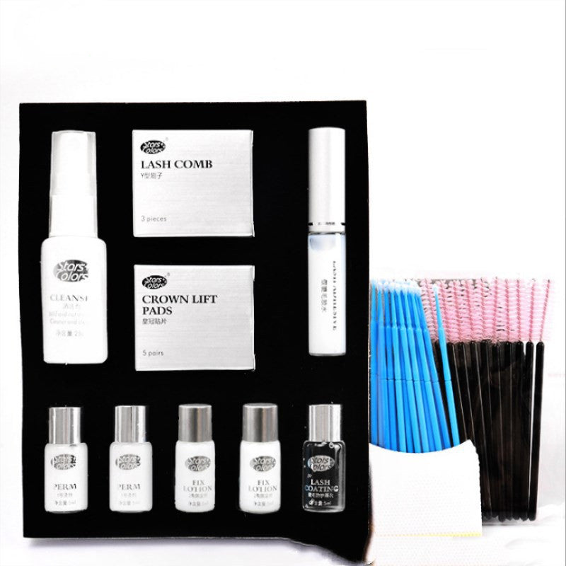 Eyelash extension kit with various items including bottles, a comb, and pads on a white background.
