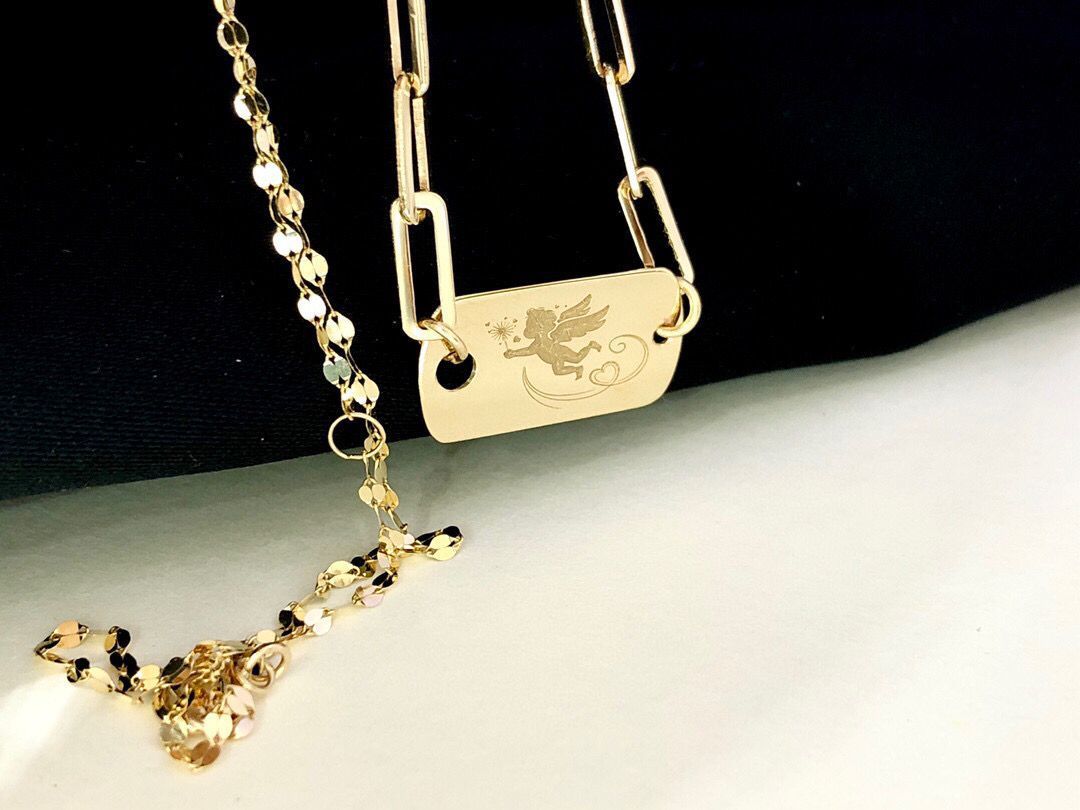 Gold necklace with a tag and pendant on a black and white background