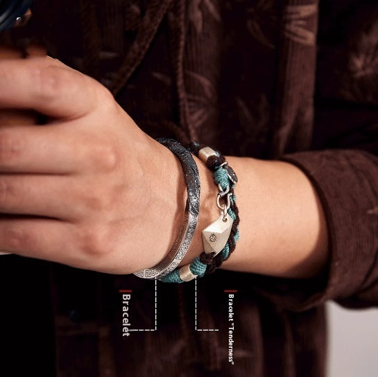 Close-up of a person's wrist wearing two bracelets with a brown background