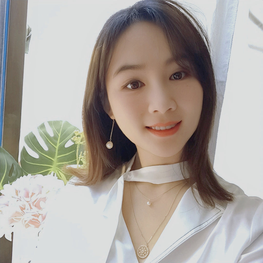 Woman wearing a white shirt with floral and plant decorations in the background