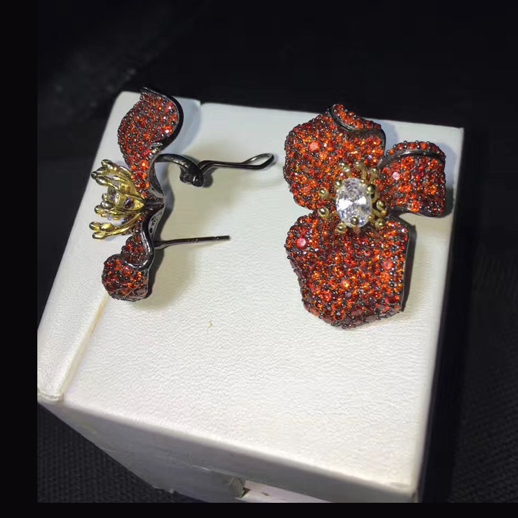 Floral earrings with red gemstones on a white box