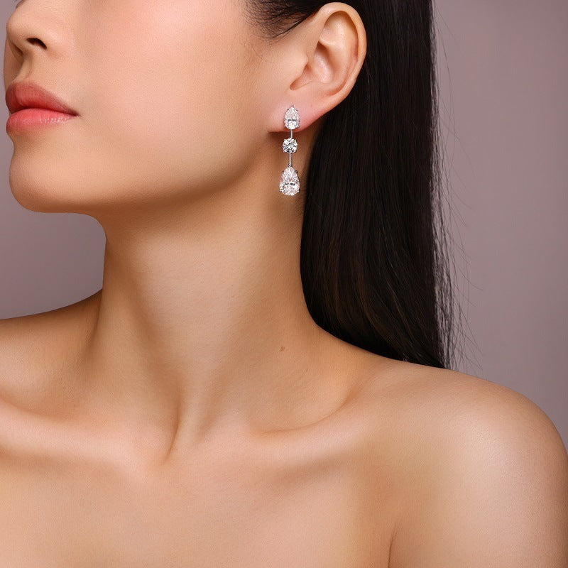 Close-up of a woman wearing a set of earrings with a neutral background