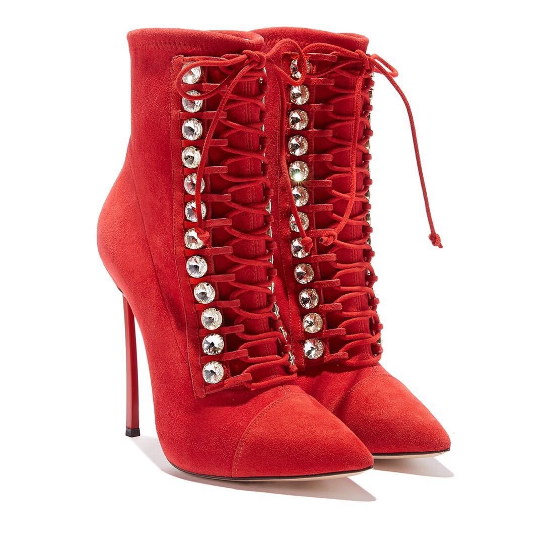 Red high-heeled boots with embellishments on a white background