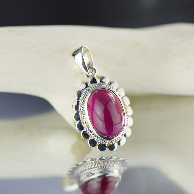 Silver pendant with a pink gemstone on a white surface