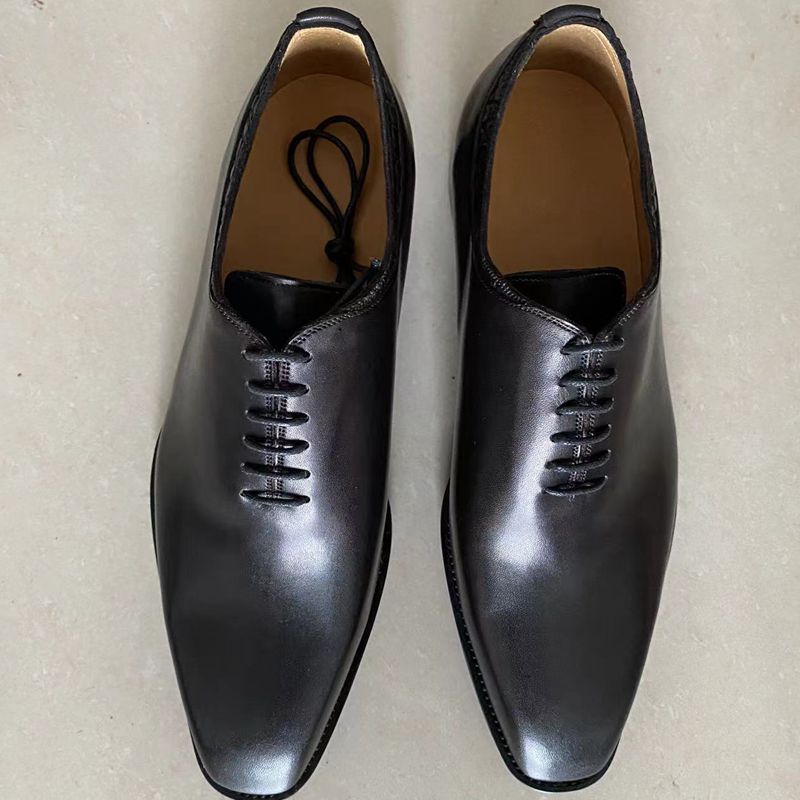 Pair of black dress shoes on a light beige background