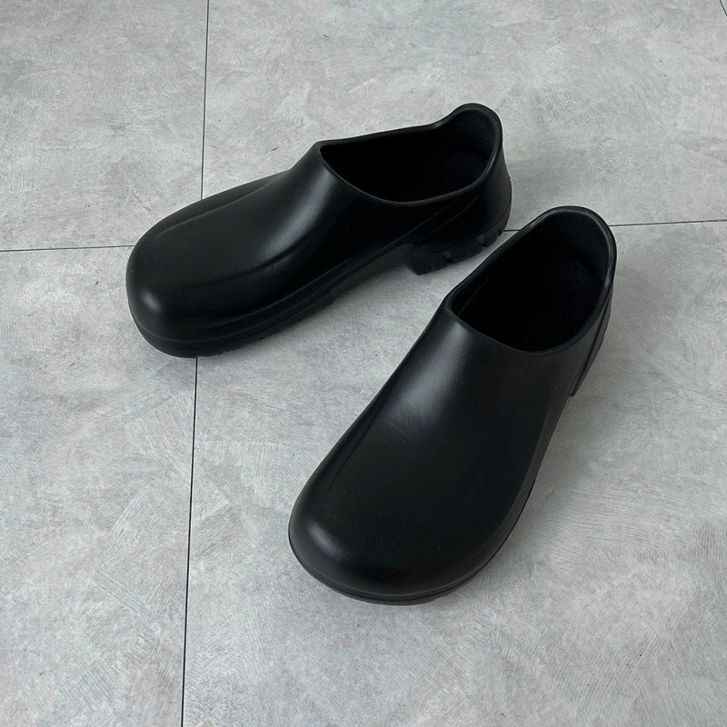 Pair of black clogs on a gray tiled floor