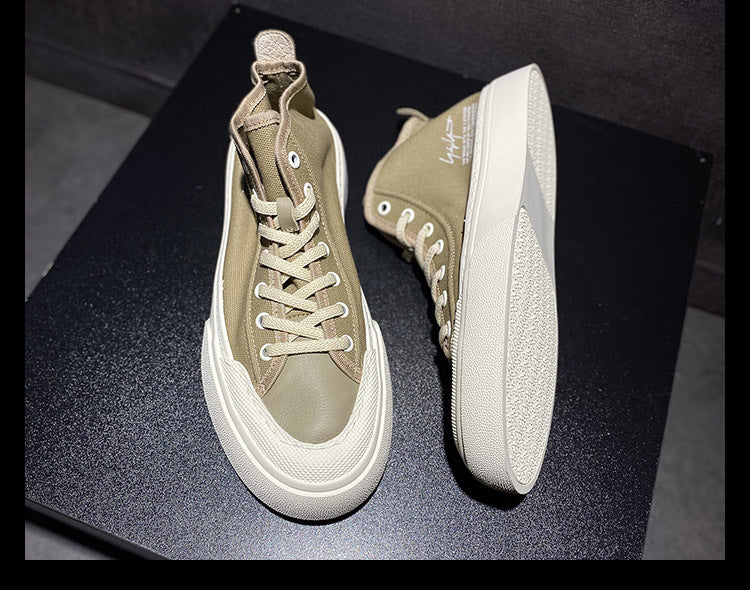 Pair of beige high-top sneakers on a dark surface